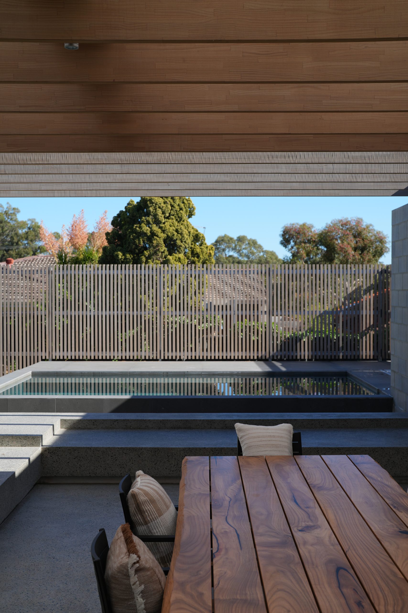 Outdoor dining table under timber beams looking toward the pool at the Gwelup renovation by Skytree Homes