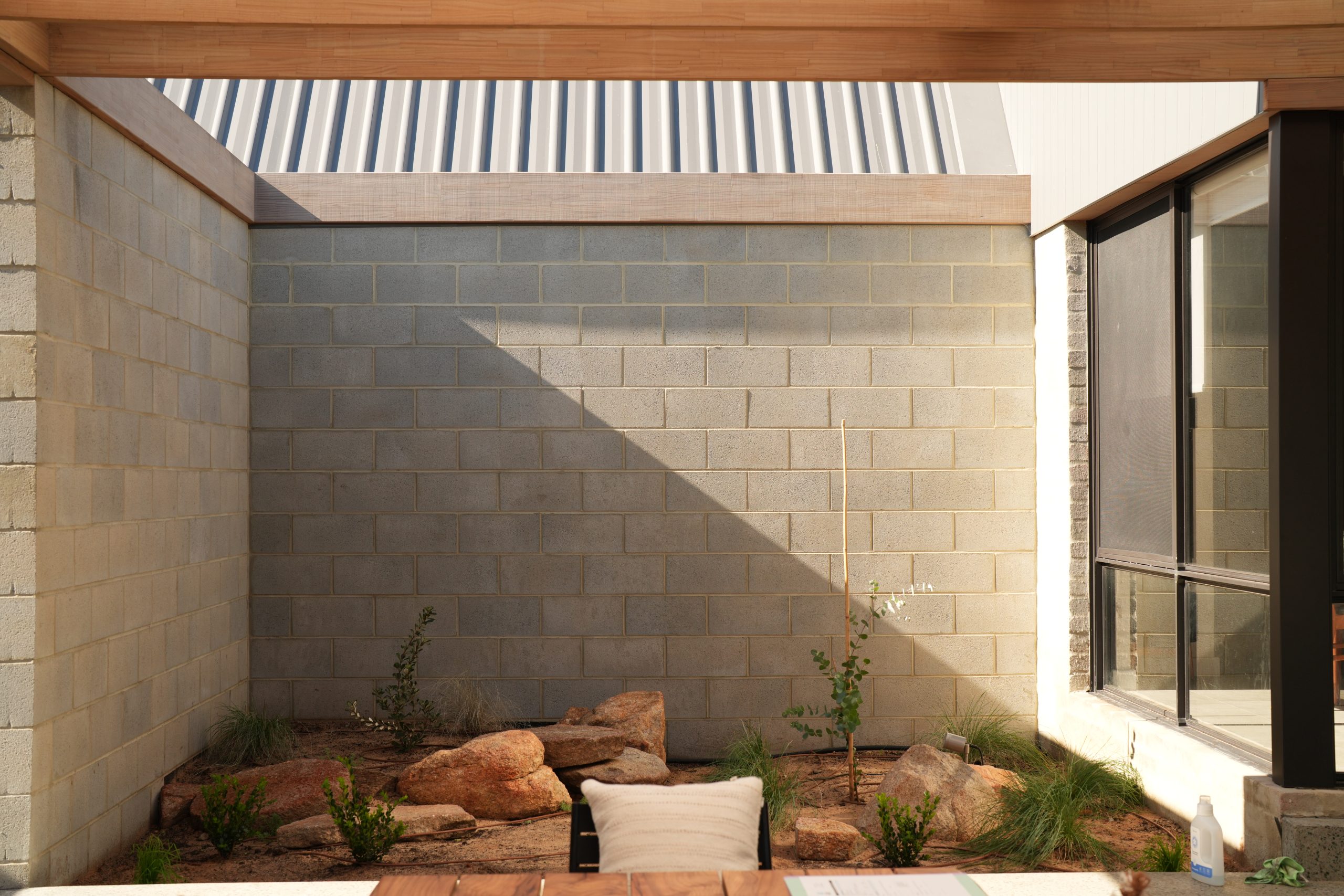 Courtyard garden with rocks and native planting against block walls at the Gwelup renovation by Skytree Homes