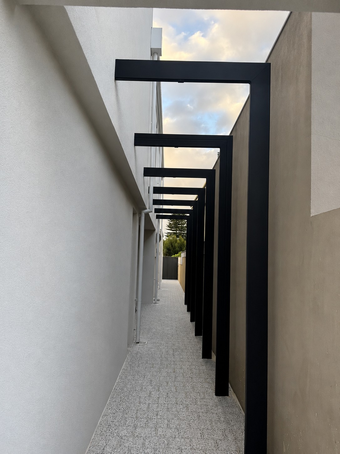 Side walkway with black steel frames at the Melville home by Skytree Homes