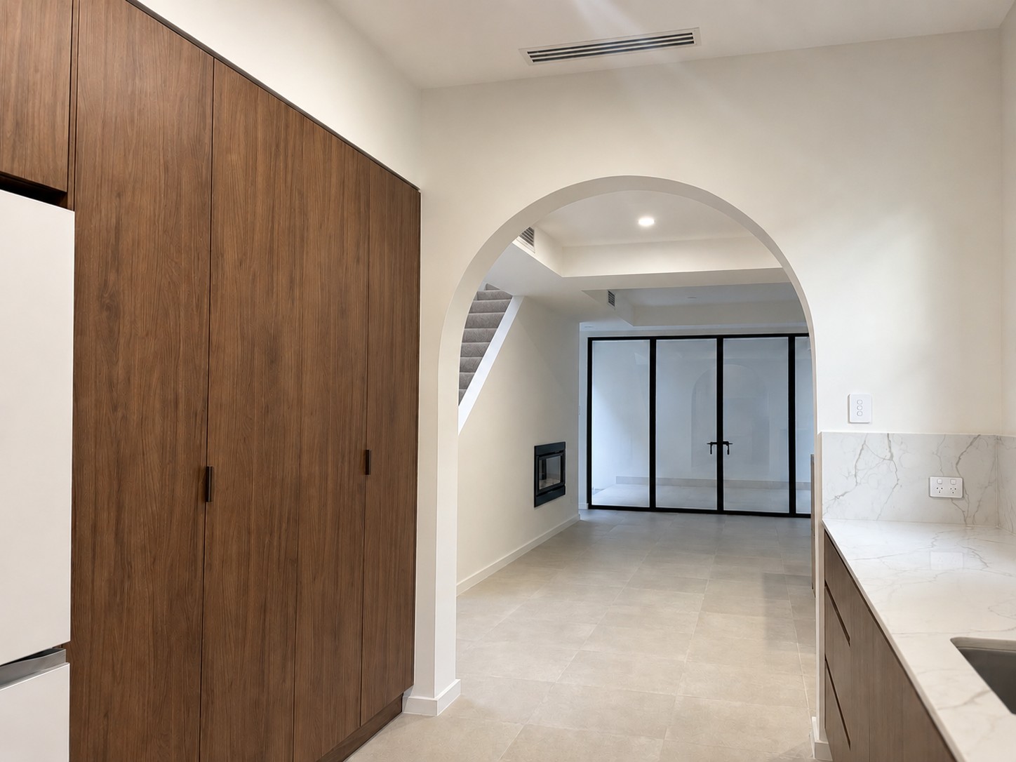 Arched hallway opening and timber-look cabinetry at the Melville home by Skytree Homes
