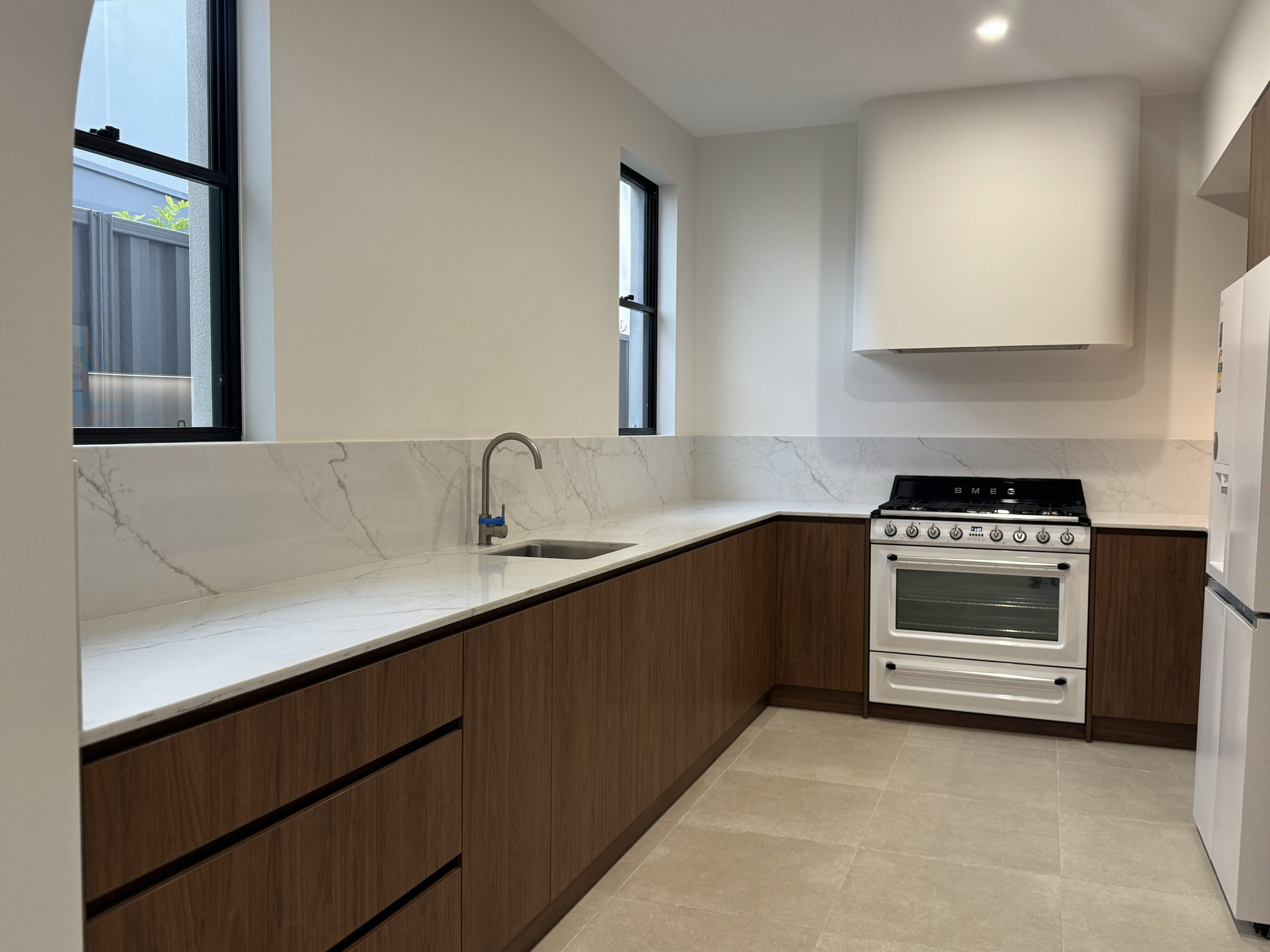 Kitchen with timber-look cabinetry, stone benchtops and freestanding oven at the Melville home by Skytree Homes