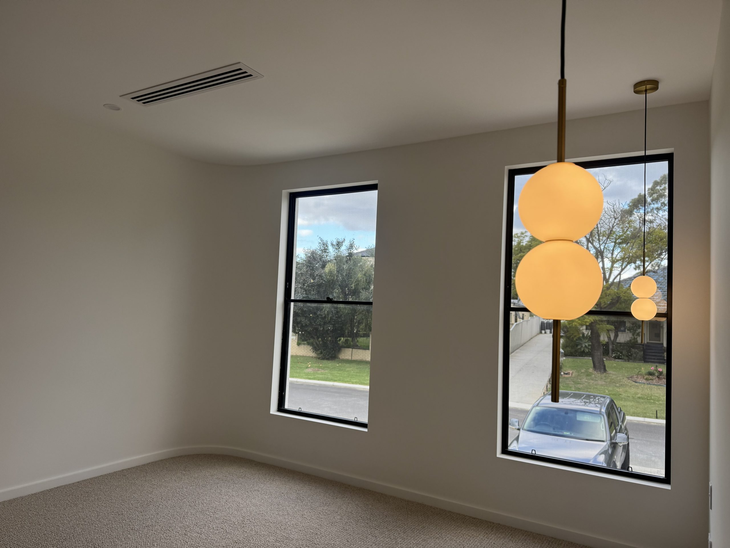 Carpeted room with black-framed windows and globe pendant lights at the Melville home by Skytree Homes