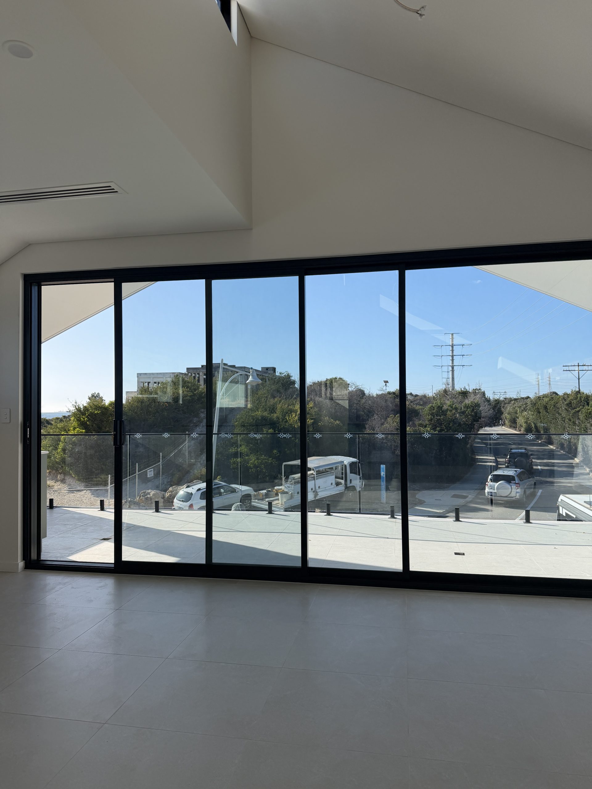 Living area with raked ceiling and full-height sliding glass doors at the North Coogee home by Skytree Homes